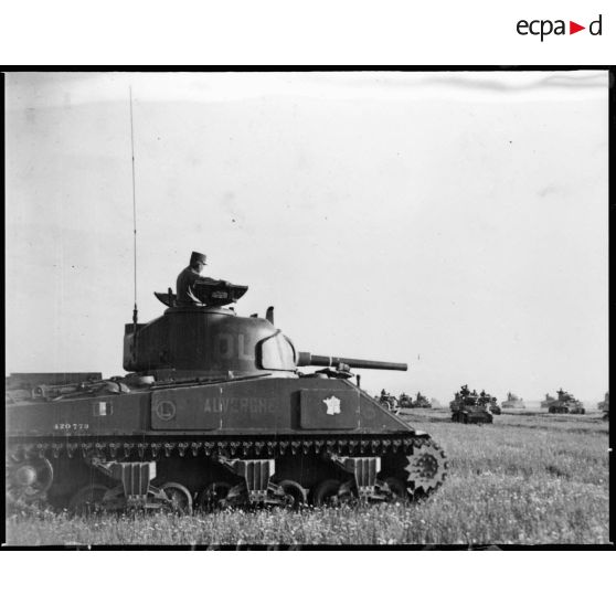 Le général de brigade Paul de Langlade, commandant du GTL de la 2e DB, assiste au défilé motorisé de son groupement tactique sur la tourelle du char Sherman M4A2 Auvergne.