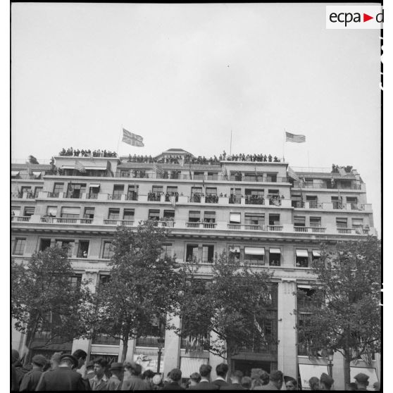 Façade d'un immeuble pavoisée aux couleurs des Alliés sur les Champs-Elysées à l'occasion de la visite du général Eisenhower à Paris.