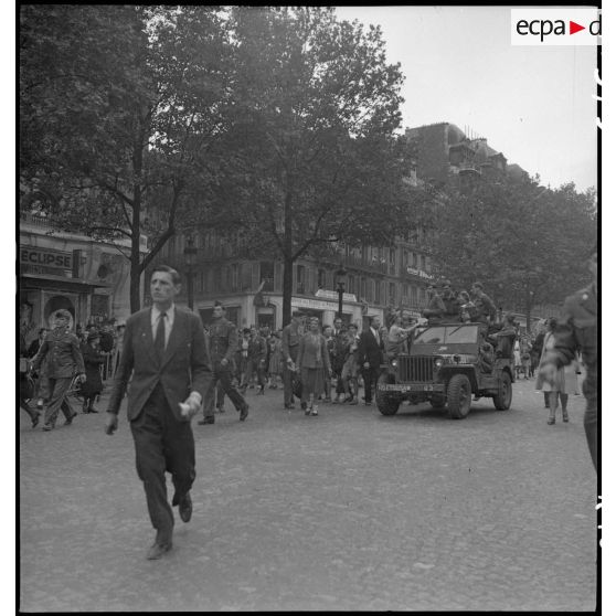 A l'occasion de la visite du général Eisenhower à Paris, les Parisiens se mêlent aux troupes américaines sur les Champs-Elysées.
