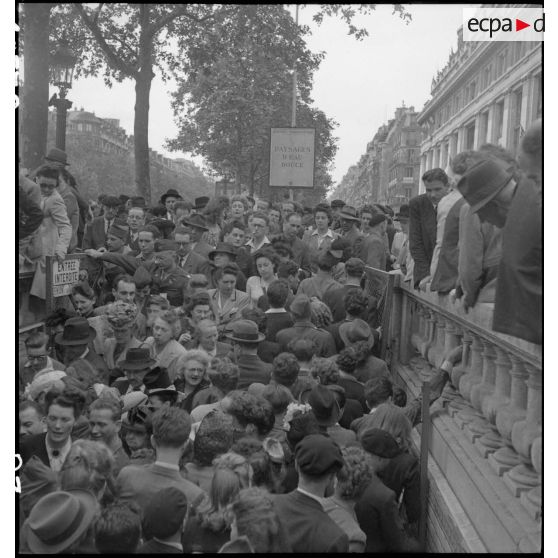 A l'occasion de la visite du général Eisenhower à Paris, la foule se presse à l'entrée d'une bouche de métro sur les Champs-Elysées.