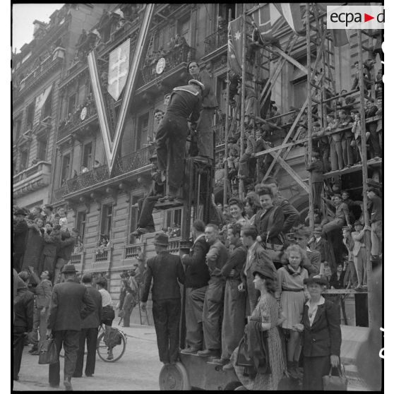 Civils et militaires sont juchés sur des échafaudages sur les Champs-Elysées, à l'occasion de la visite du général Eisenhower à Paris.