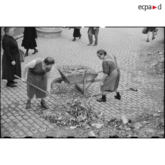Des femmes déblaient des gravats dans une rue.
