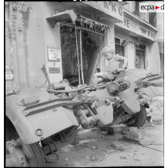 Des enfants jouent sur l'épave d'un canon antiaérien allemand.