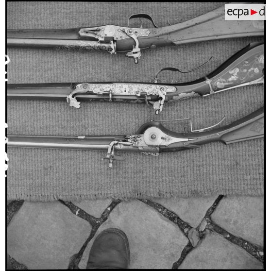 Détail des crosses de trois fusils anciens.