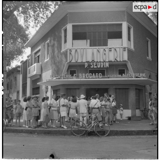 Habitants français d'Indochine faisant la queue devant une boulangerie de Saigon.