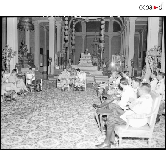 Dans la salle du trône du palais royal, entre le prince MONIVETH et le général ALESSANDRI, le roi du CAMBODGE, NORODOM SIHANUK et le général LECLERC sont en discussion.