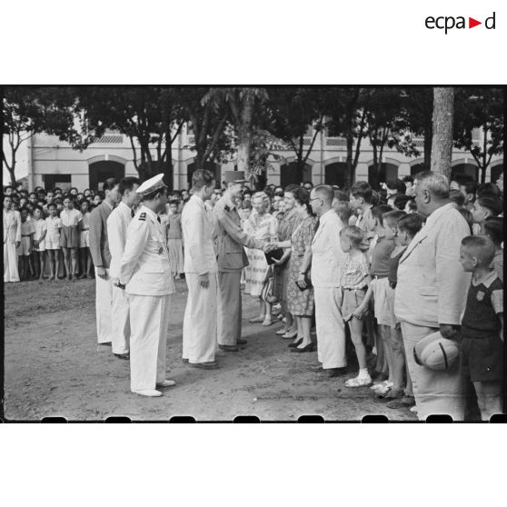 Le général LECLERC serre la main à une institutrice de l' école franco-cambodgienne SISOWATH de PHNOM-PENH, discute avec les autres personnes.