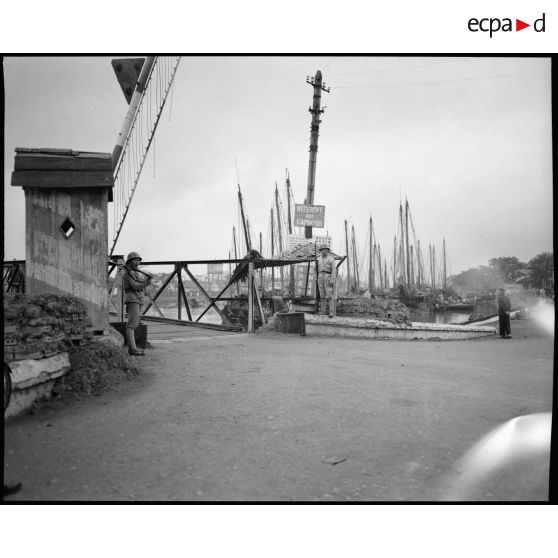 Sentinelle chinois gardant le passage d' un pont à l' entrée du port. Sentinelle devant une guérite avec la barrière du