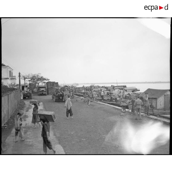 Déchargement de caisses de bois de barques par des tonkinois (hommes, femmes, et enfants.