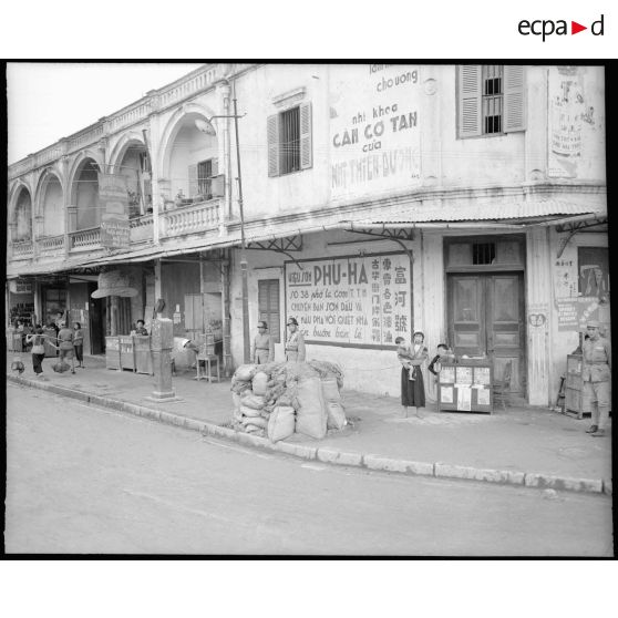 Sentinelles chinoises au coin de rue. A côté, une femme tonkinoise et son bébé dans le