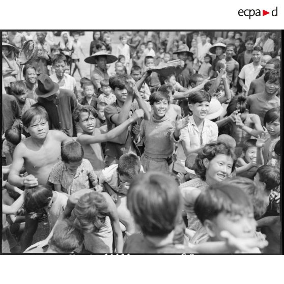 Distribution de friandises à des enfants au cours d'une tournée de propagande du Service social des armées dans le sud de la Cochinchine.