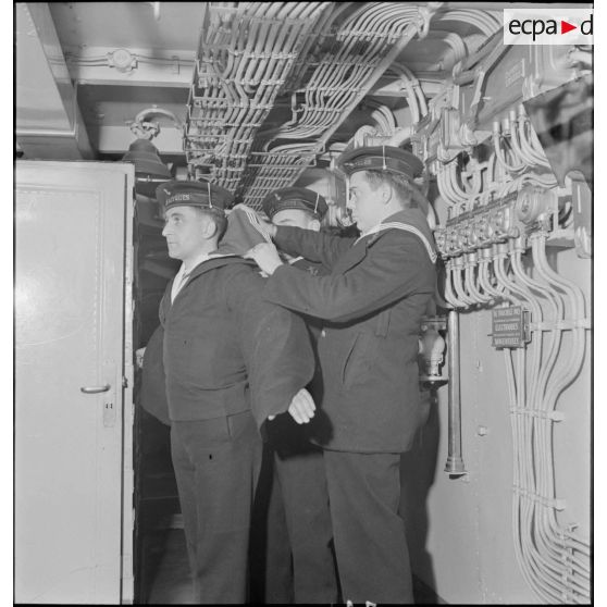 Le matelot Jean Kerlevéo, prêtre marin (à gauche), et ses camarades se préparent pour une inspection et une revue des troupes à bord du croiseur Georges Leygues.