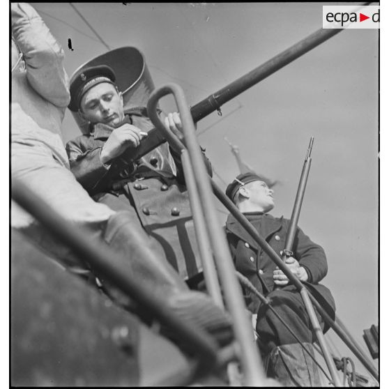 Des marins, à bord d'un chalutier réquisitionné et armé par la Marine nationale, tirent au fusil sur une mine qui dérive après avoir cassé son orin.
