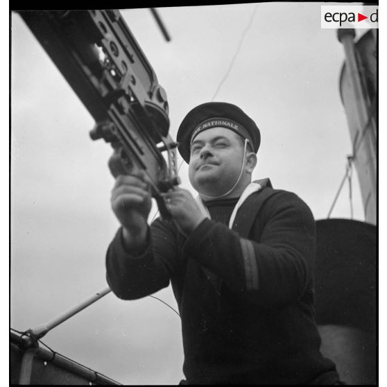 Portrait d'un quartier maître de 2e classe servant une mitrailleuse à bord d'un chalutier réquisitionné.