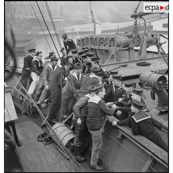 Scène de fraternisation entre marins britanniques et français à bord de navires de la Royal Navy et de la Marine naitonale. A l'arrière-plan, un grenadeur et un lanceur de grenades sous-marines.