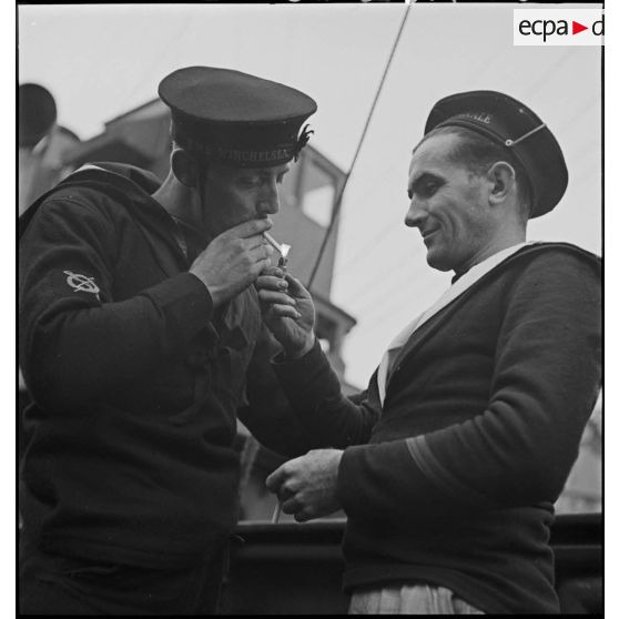 Marin français donnant du feu à un marin du destroyer HMS Winchelsea de la Royal Navy.