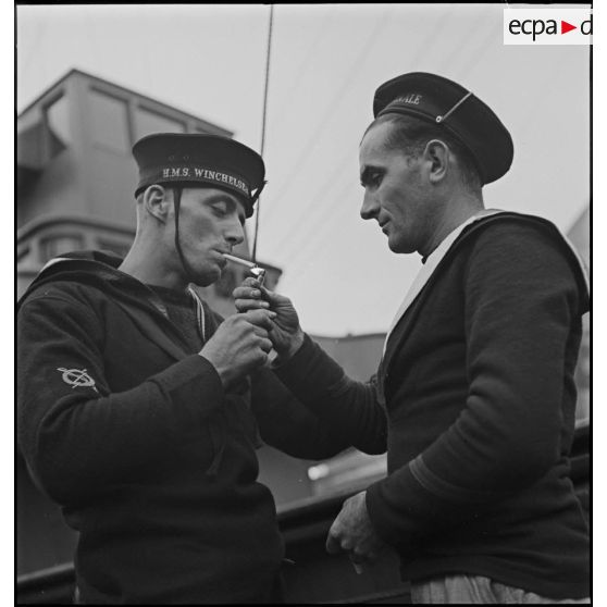 Marin français donnant du feu à un marin du destroyer HMS Winchelsea de la Royal Navy.