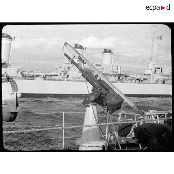 Vue d'un canon antiaérien de 37 mm. A l'arrière-plan, vue bâbord d'un contre-torpilleur de la classe Vauquelin (peut-être Le Tartu).