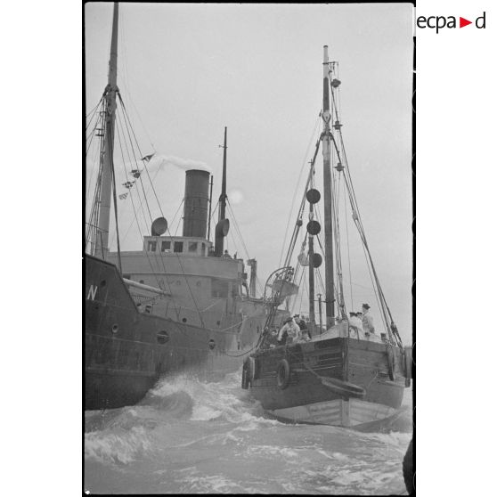 Un chalutier réquisitionné par la Marine nationale pour la police de la navigation accoste un navire pour un contrôle.