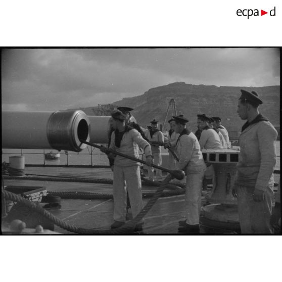 Ecouvillonnage d'un canon d'artillerie navale à bord d'un croiseur, probablement le croiseur lourd Duquesne.