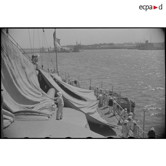 Une tente de camouflage est dressée sur la plage arrière d'un croiseur à quai.