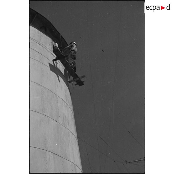 Un marin nettoie une des cheminées à bord du croiseur lourd Duquesne.