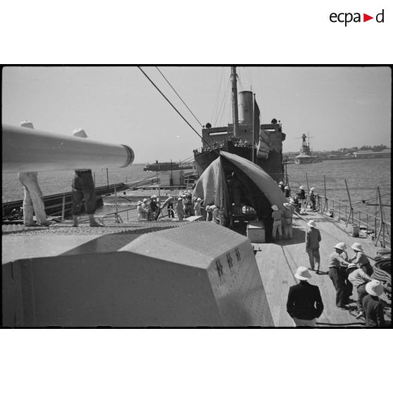 Une tente de camouflage est dressée sur l'armement de la plage arrière du croiseur lourd Duquesne à quai.