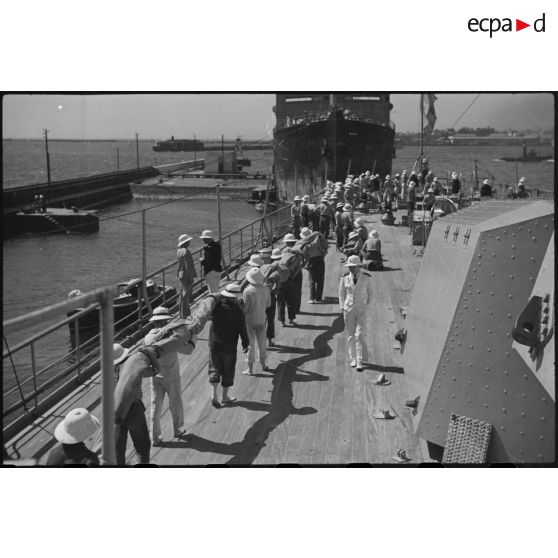 Une tente de camouflage va être mise en place sur la plage arrière du croiseur lourd Duquesne à quai.