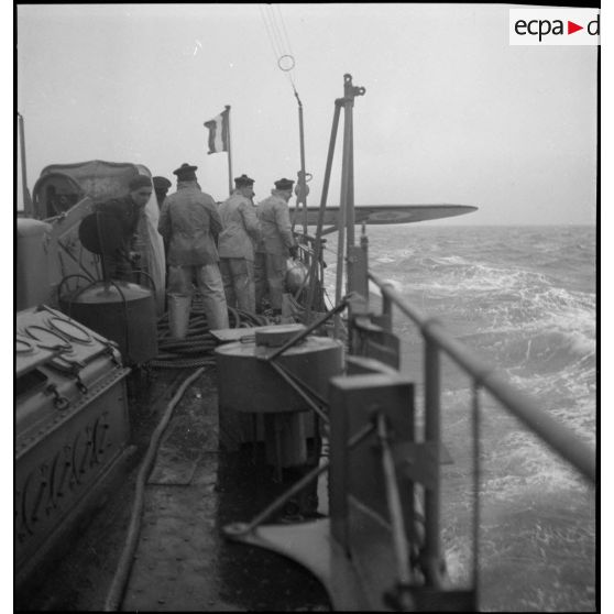 A l'issue d'un vol de reconnaissance, un hydravion Latécoère 290 est arrimé à la bigue sur le pont arrière du chasseur de sous-marins n°5 (CH 5) afin d'être remorqué.