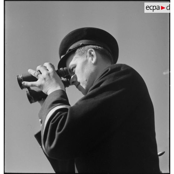 Second maître observant l'horizon aux jumelles à bord du torpilleur Simoun.