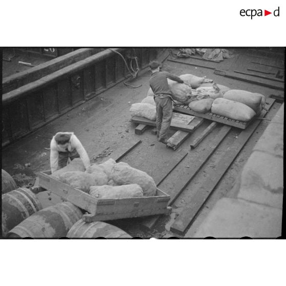 Sacs de pommes de terre destinés aux navires d'une escadre mouillant au large.