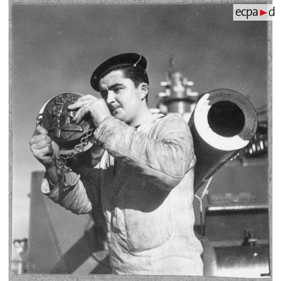 Un canonnier met en place une tape de bouche sur un canon de 130 mm à bord du cuirassé Strasbourg.