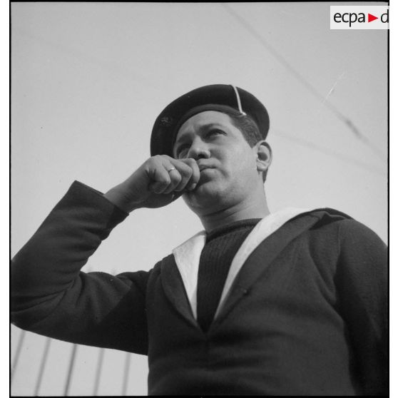 Un matelot rend les honneurs au sifflet à bord du croiseur (ou cuirassé) Dunkerque.