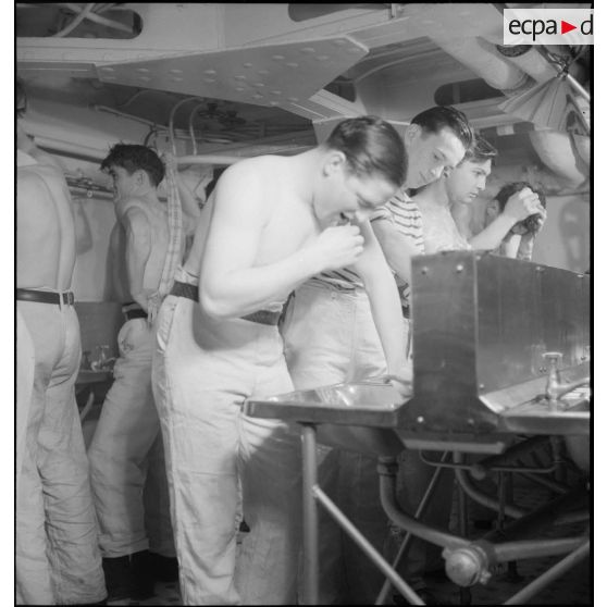 Des marins font leur toilette dans les locaux communs réservés aux hommes d'équipage à bord du croiseur (ou cuirassé) Dunkerque.