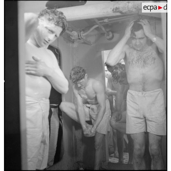 Des marins prennent une douche dans les locaux communs réservés aux hommes d'équipage à bord du croiseur (ou cuirassé) Dunkerque.