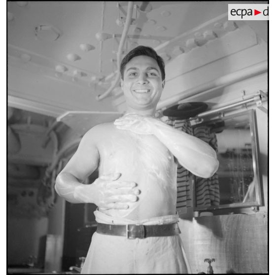 Un marin fait sa toilette dans les locaux communs réservés aux hommes d'équipage à bord du croiseur (ou cuirassé) Dunkerque.