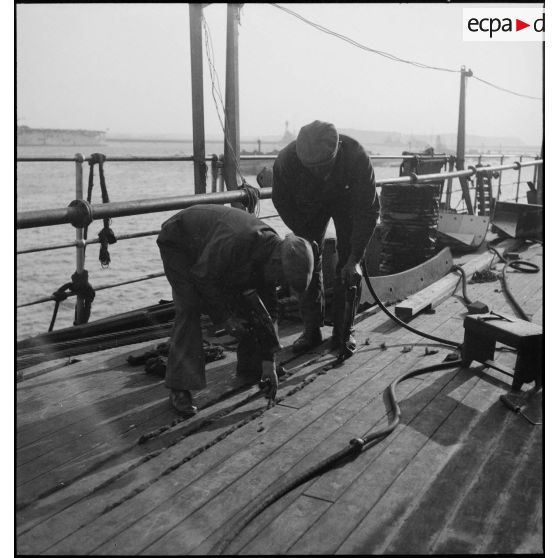 Des ouvriers parquettent le pont du cuirassé Richelieu en cours d'achèvement dans l'arsenal de Brest.
