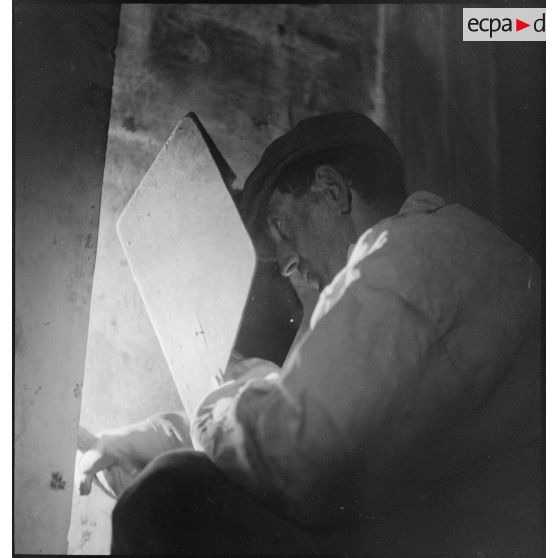 Un ouvrier effectue une soudure à bord du cuirassé Richelieu en cours d'achèvement dans l'arsenal de Best.