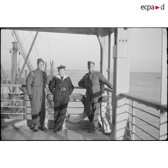 Soldats canadiens et photographe du service cinématographique de la Marine (SCA/Marine) sur le pont d'un paquebot transport de troupes naviguant vers l'Ecosse.