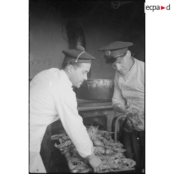 Les marins cuisiniers vont préparer les homards pour le repas de réveillon de Nouvel An à bord du croiseur la Gloire.