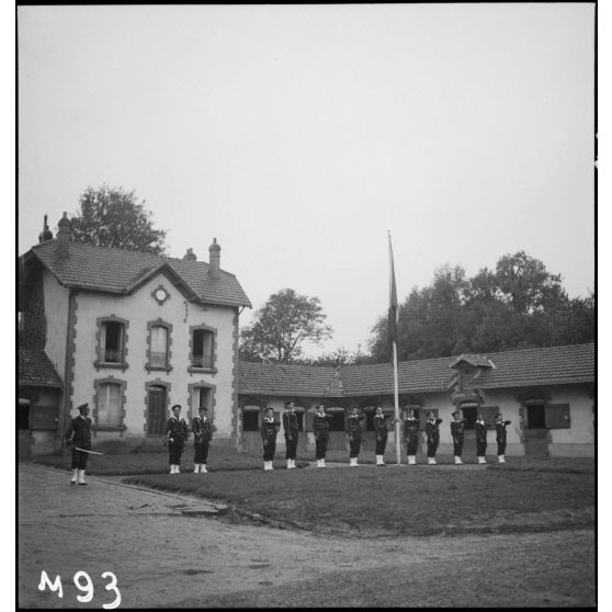 Un détachement de fusiliers marins rend les honneurs près du mât des couleurs lors de la visite du président de la République dans leur camp d'entraînement.