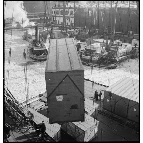 Dans le port de New-York pris par les glaces, des caisses qui contiennent des avions destinés aux Alliés sont chargées à bord d'un cargo.