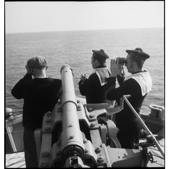 Des canonniers observent l'horizon depuis la plate-forme sur laquelle se trouve le canon de 90 mm du pétrolier Bourgogne.