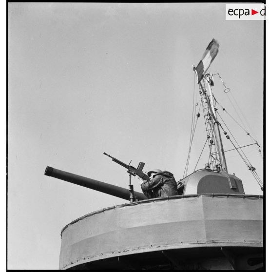 Servant d'un fusil-mitrailleurs FM 24/29 en position sur une des tourelles de canons de 100 mm à bord d'un torpilleur léger.