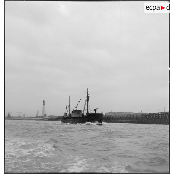 Un chalutier armé par la Marine nationale sort d'un port pour une mission de patrouille.