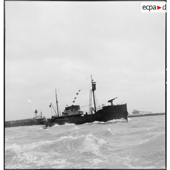 Un chalutier armé par la Marine nationale sort d'un port pour une mission de patrouille.