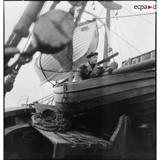 Matelot dans un canot à bord d'un chalutier armé par la Marine nationale.