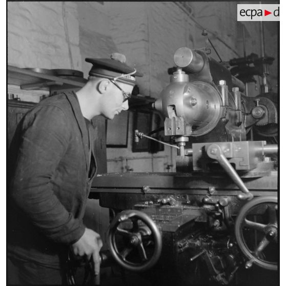 Atelier central de la flotte : un marin travaille une pièce de métal à la fraiseuse.