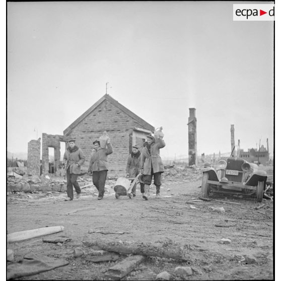 Corvée de ravitaillement en vivres de marins d'un des navires ancrés dans le port de Namsos.