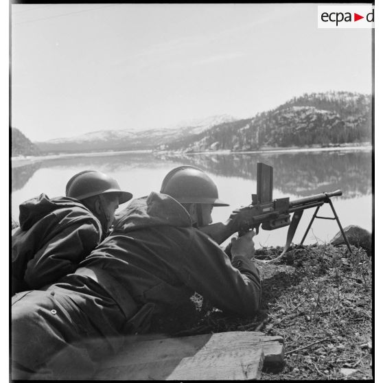 Des chasseurs alpins de la 1ère DLCh (Division légère de chasseurs), servants d'un FM 24-29, sont postés en surplomb d'une voie ferrée longeant un fjord.